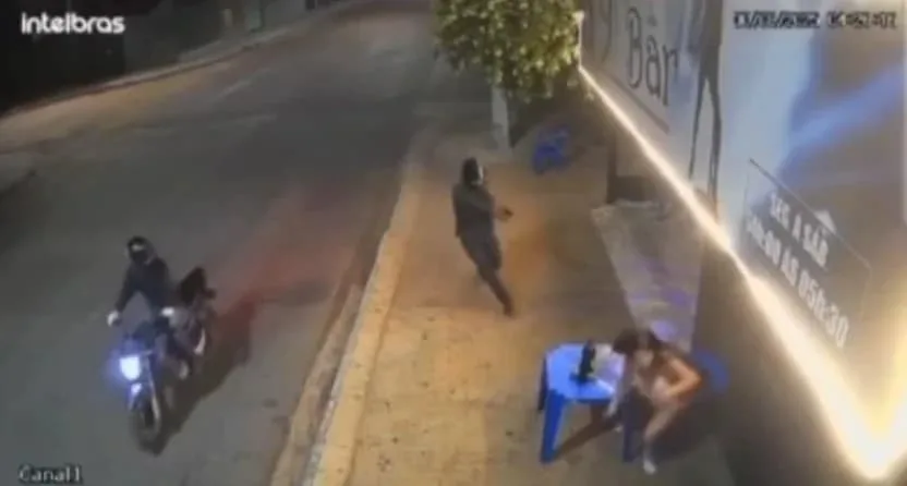 Dupla em moto baleia mulher em frente a bar em Pontes e Lacerda